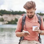 Man holding enamel mug using cellular phone, Krakow, Malopolskie, Poland, Europe